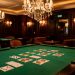 Salon élégant inspiré d’un casino, avec une table recouverte de feutre vert, des cartes retournées, des boiseries sombres et des lustres éclairés par une lumière ambrée.