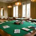 Salle parisienne accueillante préparée pour un atelier de stratégie destiné aux débutants, avec tables en feutre vert, jetons colorés, cartes retournées et accessoires évoquant une gestion prudente du budget.