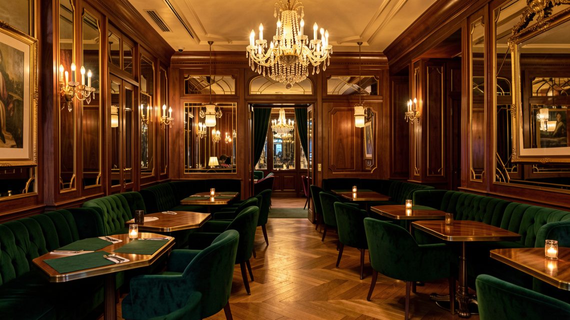 Salon parisien élégant aux tables en velours vert, fauteuils raffinés, boiseries et lustres dorés dans une ambiance chaleureuse de week-end.
